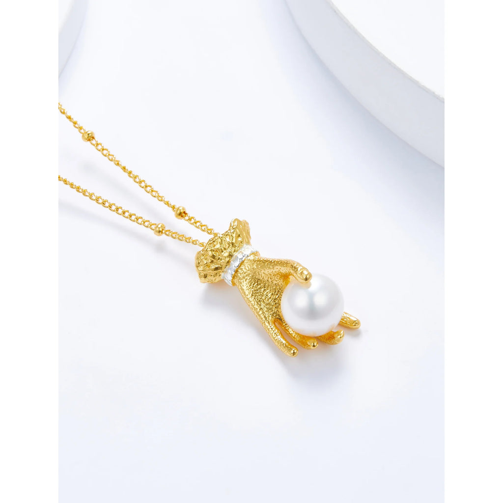 Goldene Halskette mit perlenhaltendem Handanhänger in Nahaufnahme auf weissem Hintergrund – Symbol für Eleganz und Aussage