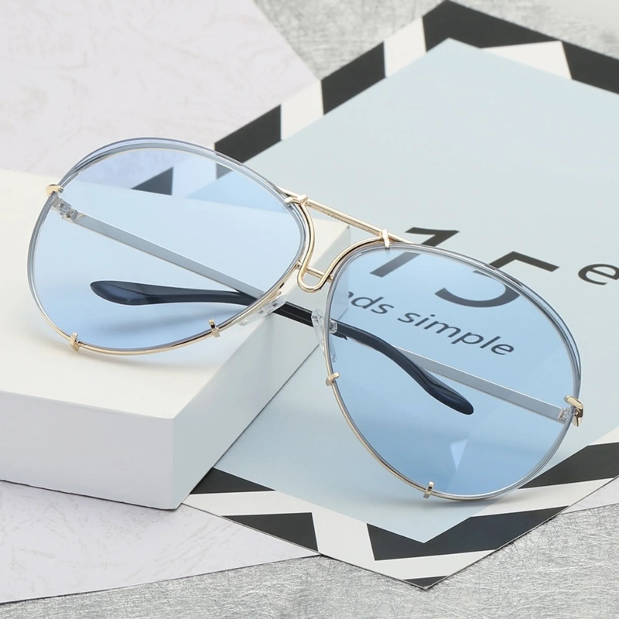 Helle Sonnenbrille mit blauem Verlaufsglas und goldfarbener Rahmenstruktur