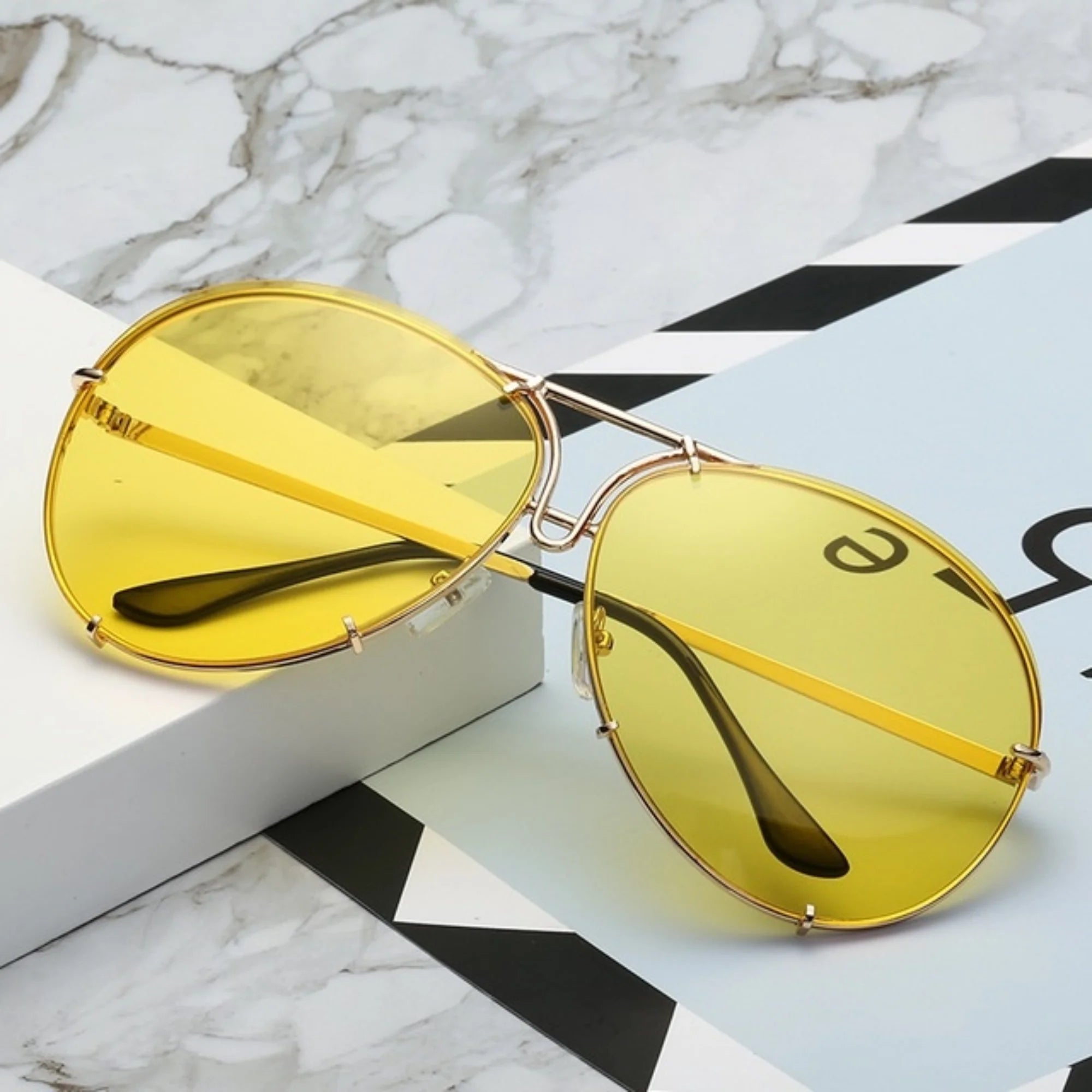 Gelb getönte Sonnenbrille mit feinem Metallrahmen, aufgelegt auf grafischem Papier