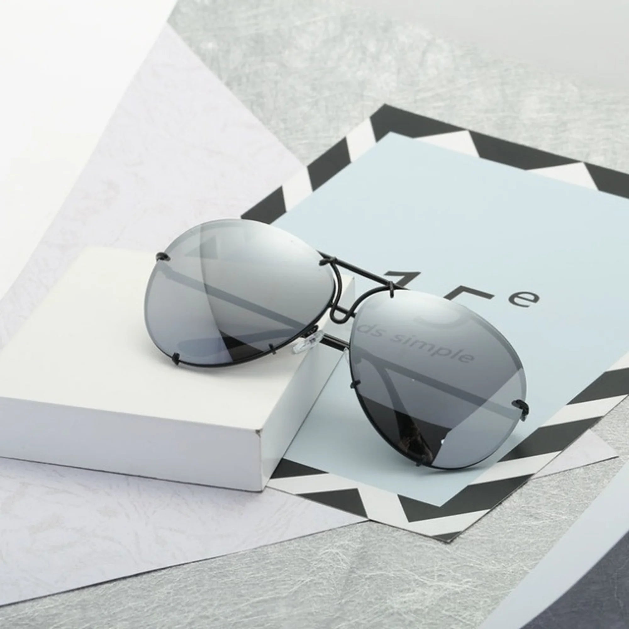 Graue Sonnenbrille mit Spiegelglas und mattschwarzem Rahmen, ruhig präsentiert