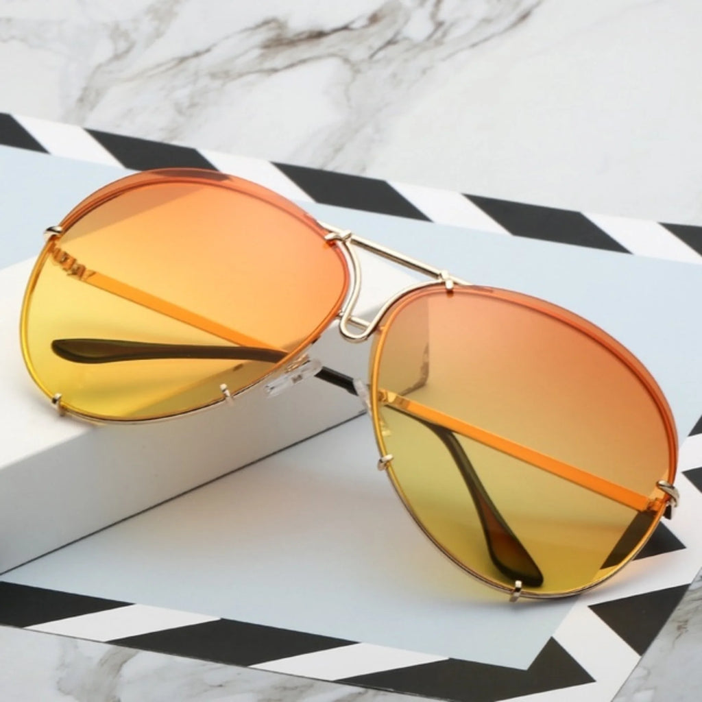 Sonnenbrille mit leuchtend orange-gelbem Verlaufsglas in goldener Fassung