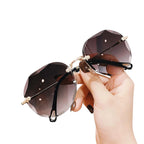 Facettierte Sonnenbrille mit braunem Glas – polygonal, randlos, ruhig geführt