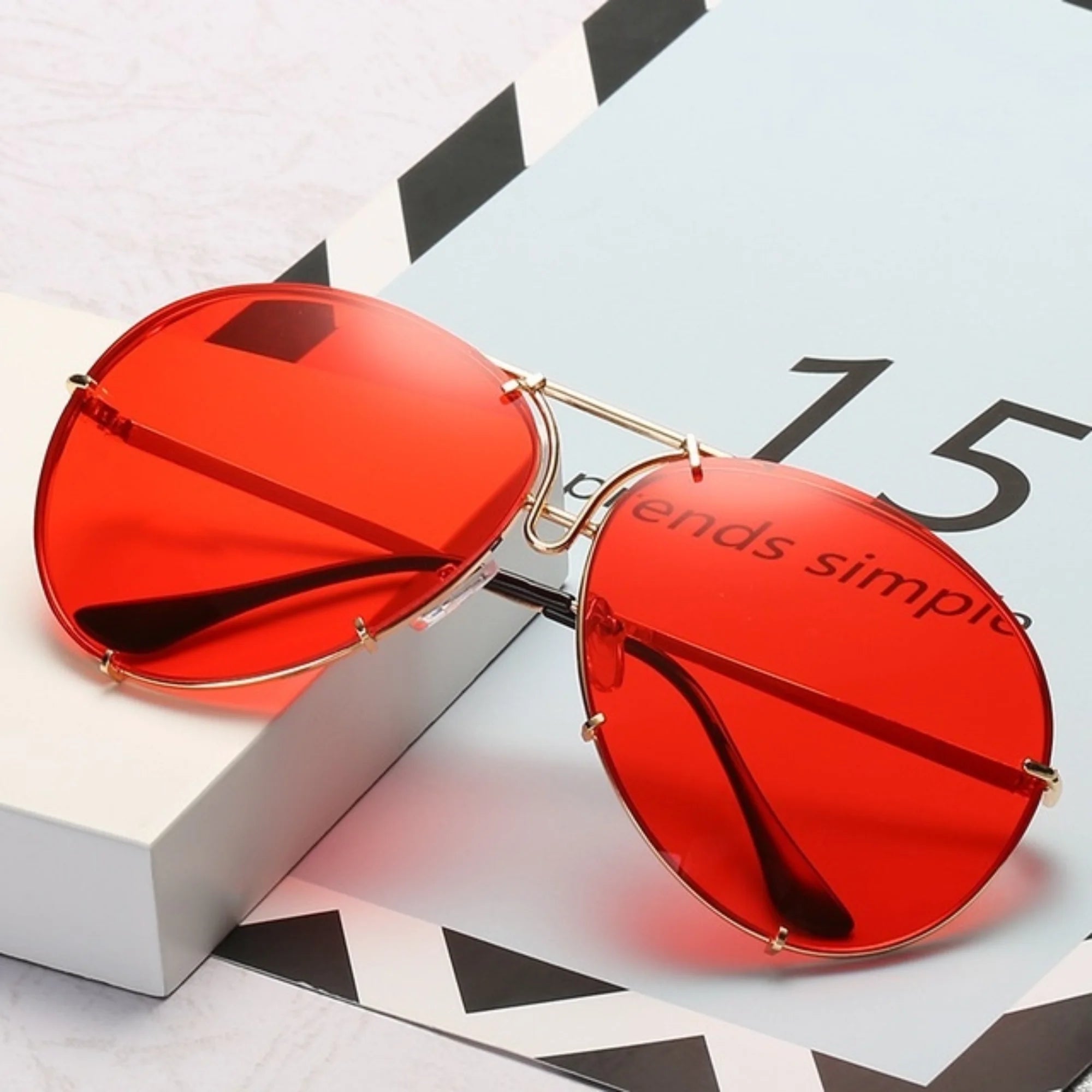 Sonnenbrille mit rotem Segmentglas und filigraner Metallfassung auf hellem Untergrund