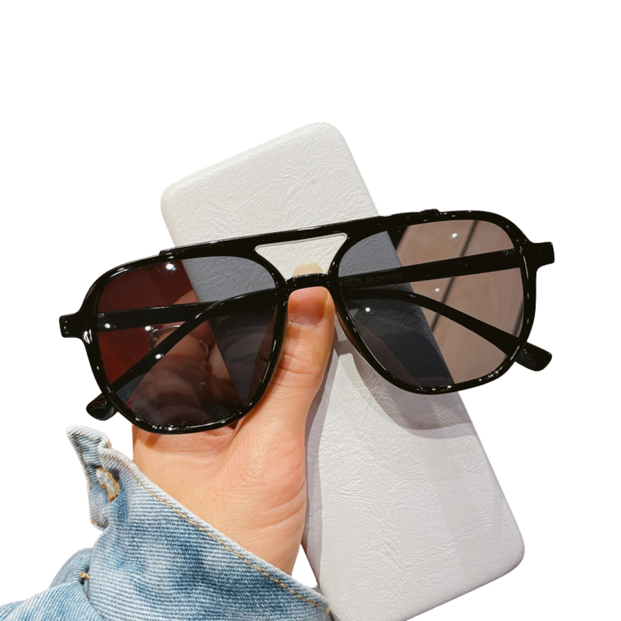 Sonnenbrille mit dunklen Gläsern – in der Hand gehalten über weisses Etui.