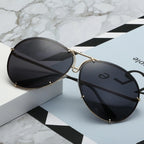 Dunkle Sonnenbrille mit schwarzem Glas und goldfarbener Metallfassung, ruhig inszeniert