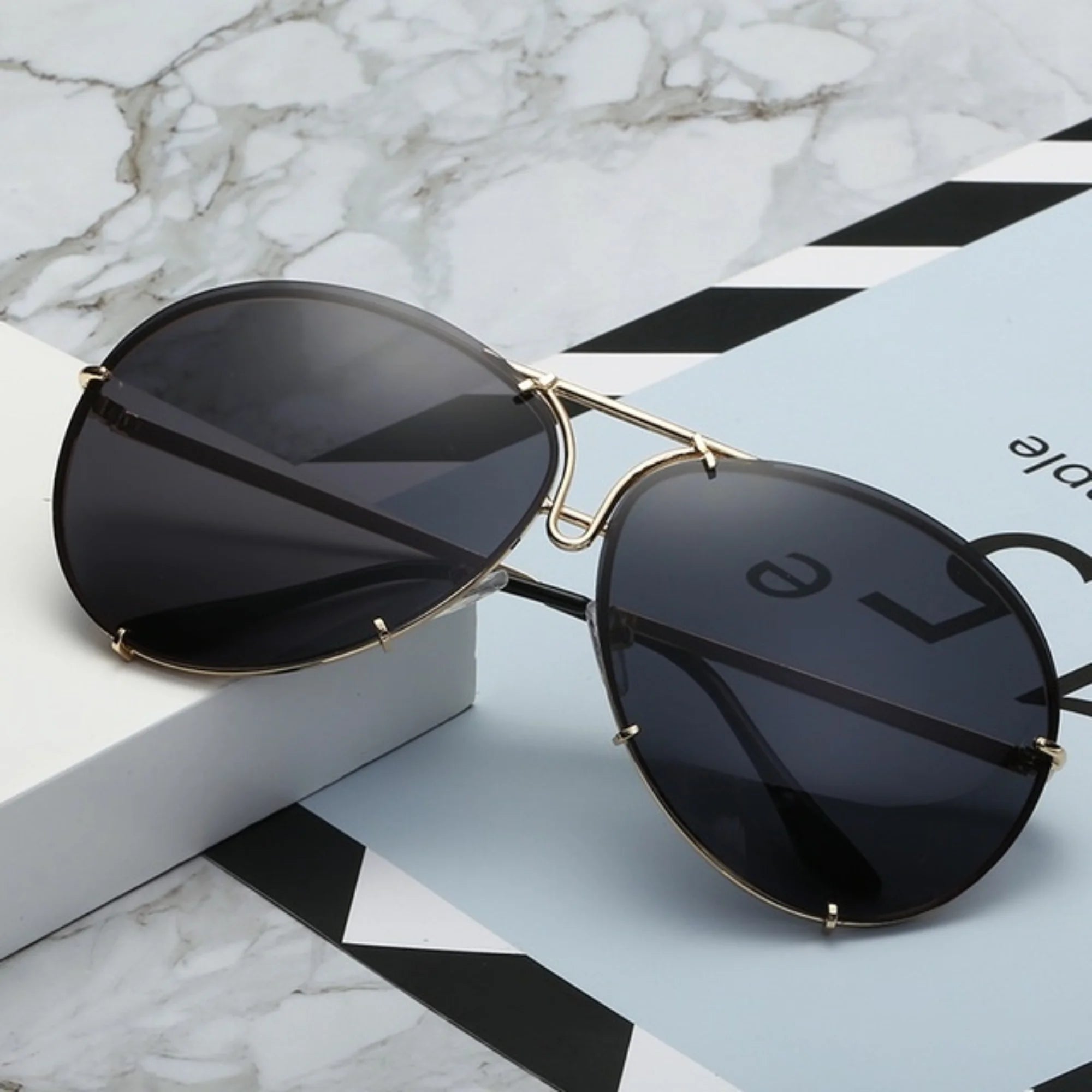 Dunkle Sonnenbrille mit schwarzem Glas und goldfarbener Metallfassung, ruhig inszeniert