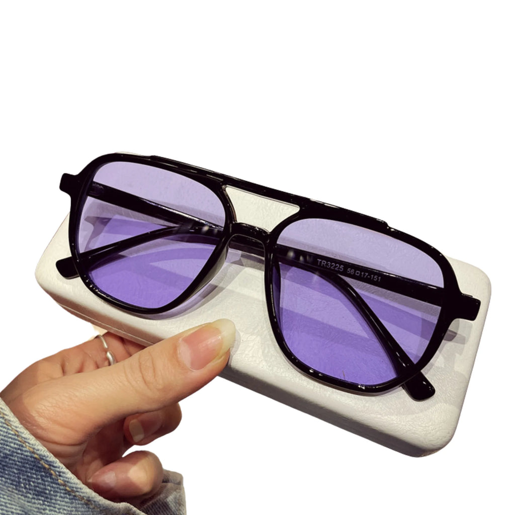 Sonnenbrille mit schwarzem Rahmen und lila Gläsern – auf Etui, Nahaufnahme.