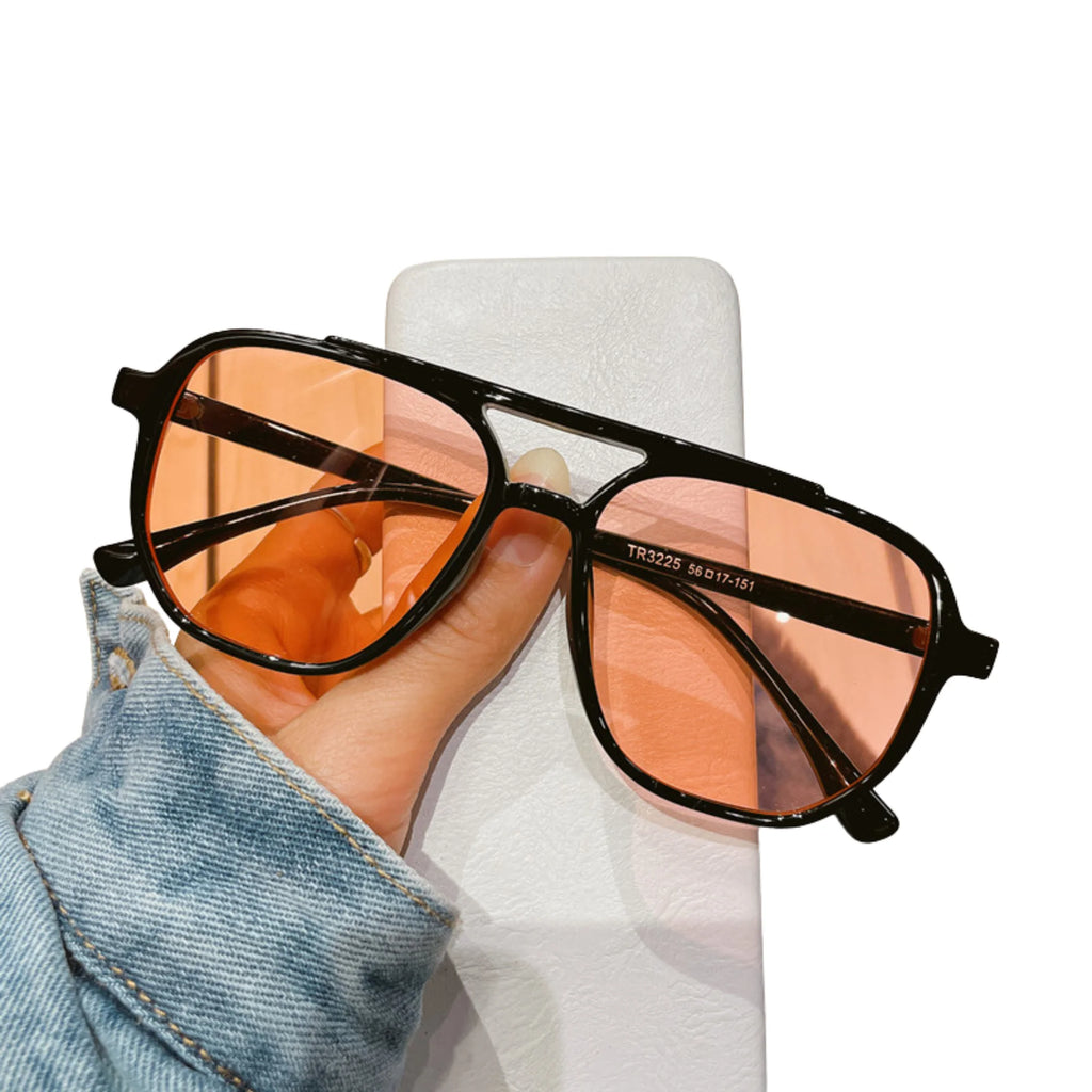 Orange getönte Sonnenbrille mit schwarzem Rahmen – gehalten in der Hand.