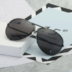 Schwarze UV400-Sonnenbrille mit glattem, spiegelndem Glas – ruhig inszeniert