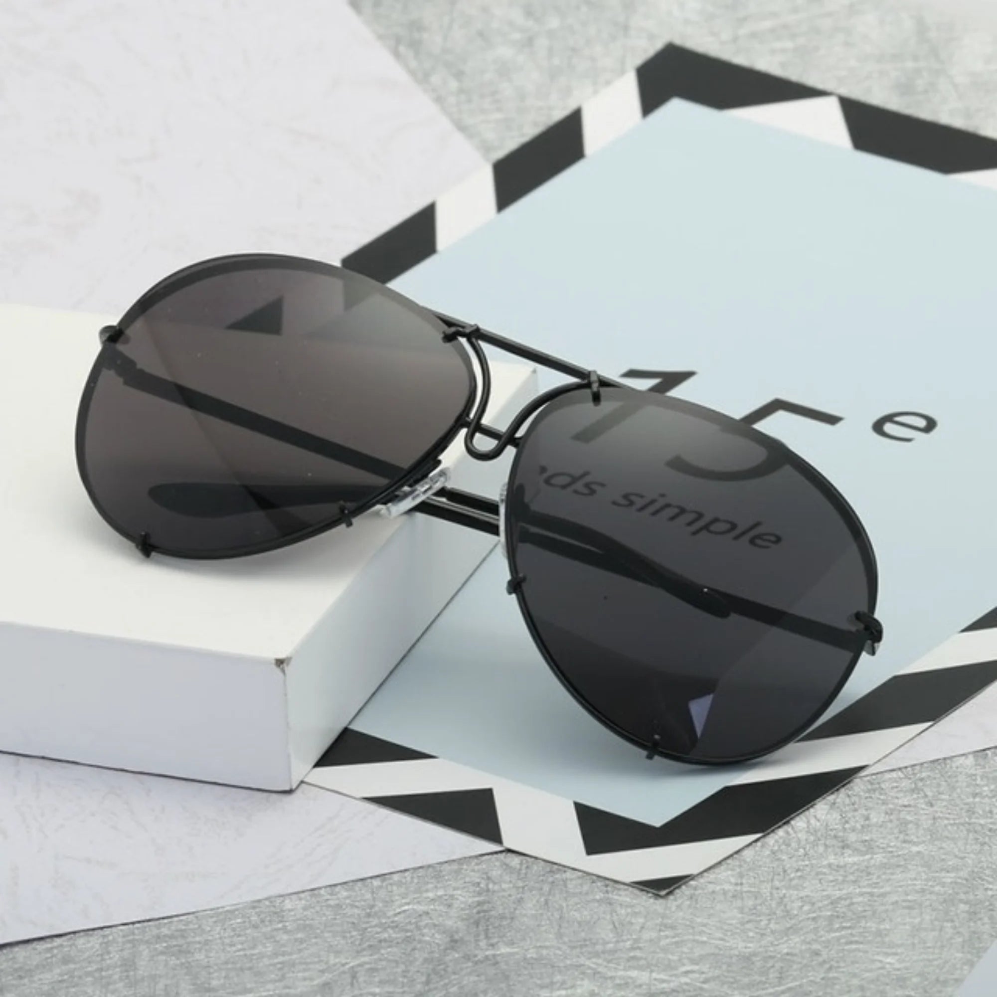 Schwarze UV400-Sonnenbrille mit glattem, spiegelndem Glas – ruhig inszeniert