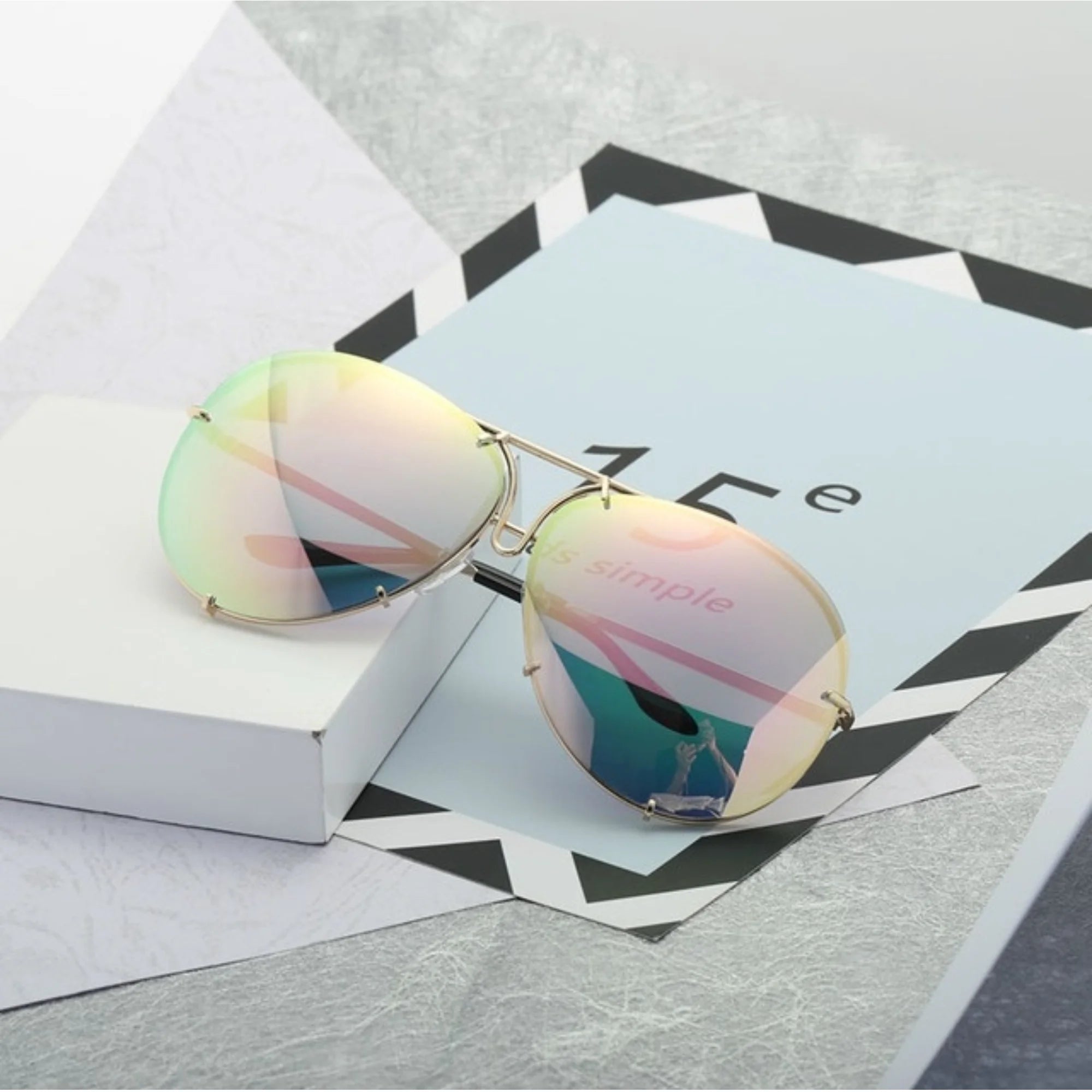 Verspiegelte Sonnenbrille mit zarten Pastelltönen auf ruhigem Untergrund