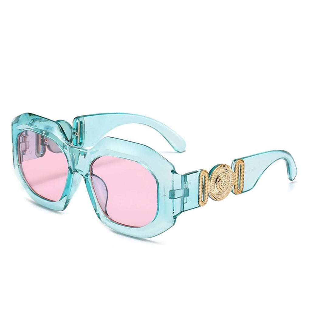 Transparente türkisfarbene Sonnenbrille mit rosa Gläsern und Goldsymbol am Bügel