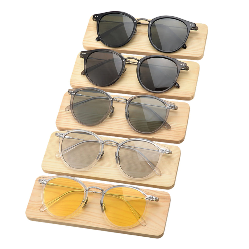 Fünf runde Sonnenbrillen von schwarz bis gelb auf Holzplatten präsentiert