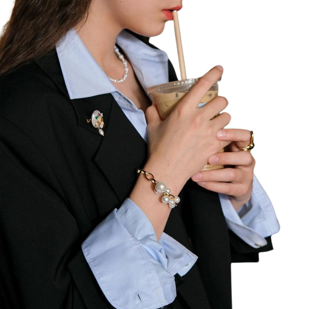 Kraftvolles Armband mit goldplattierter Gliederkette und Perlenanhang – getragen zu Blazer und Kaffee