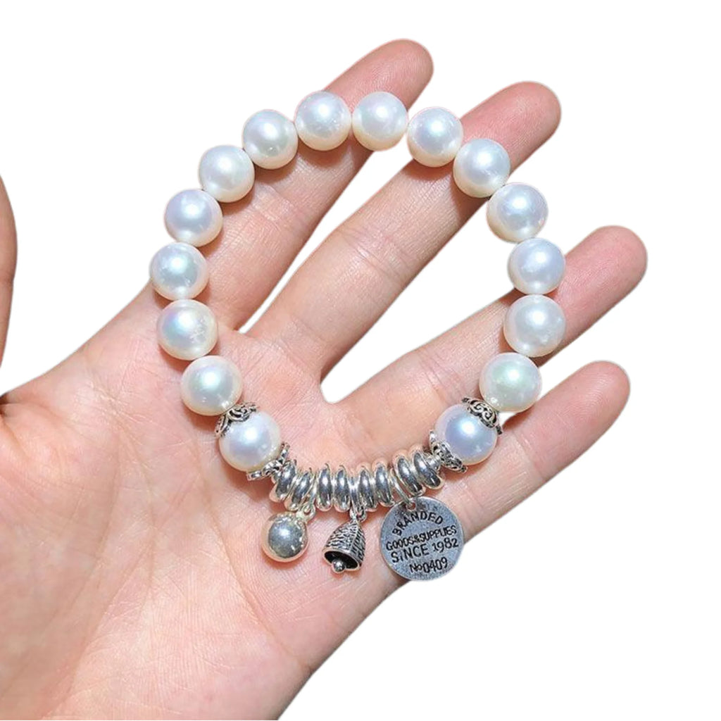 Stretcharmband mit grossen Süsswasserperlen und silberfarbenen Charms – ruhig, rund, symbolisch