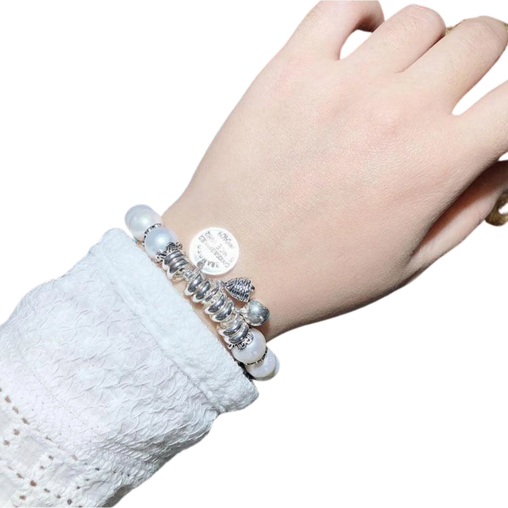 Handansicht eines dehnbaren Perlenarmbands mit Symbol-Charms – schlicht, aber bedeutungsvoll