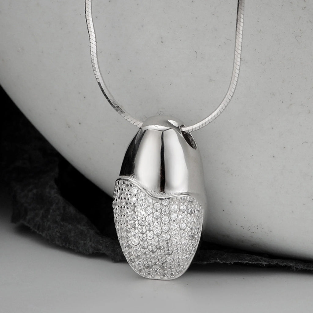 Tropfenanhänger aus 925 Silber mit Zirkoniasteinen – edel arrangiert vor dunklem Hintergrund