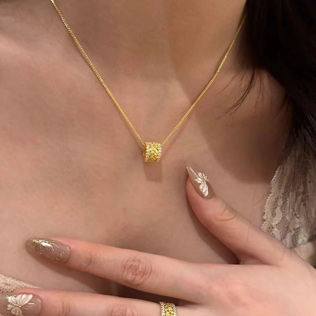 Vergoldete Kette mit durchbrochenem Zylinderanhänger – floral inspiriert, leicht und elegant