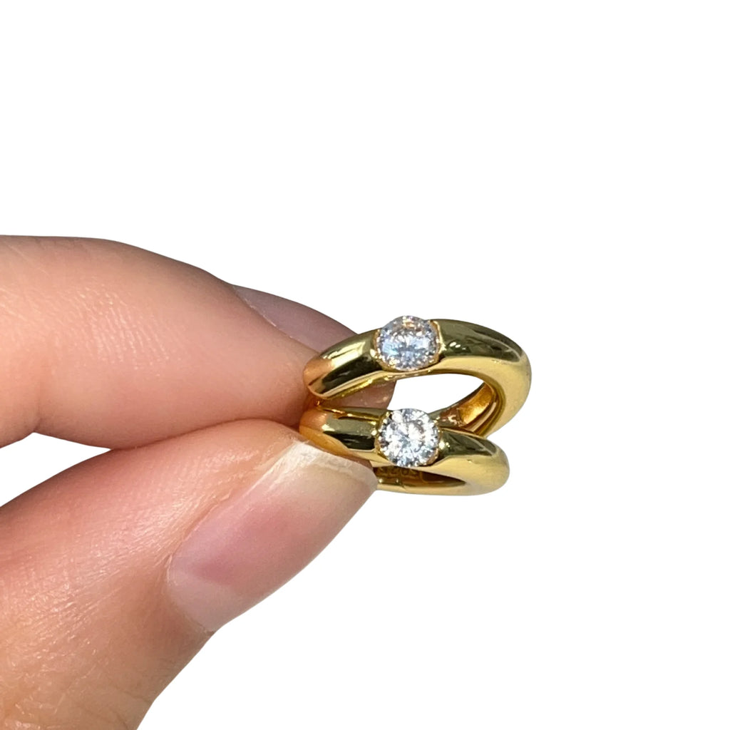 Kompakte Creolen aus vergoldetem 925 Silber mit mittigem Zirkonia – zwischen Fingern gehalten