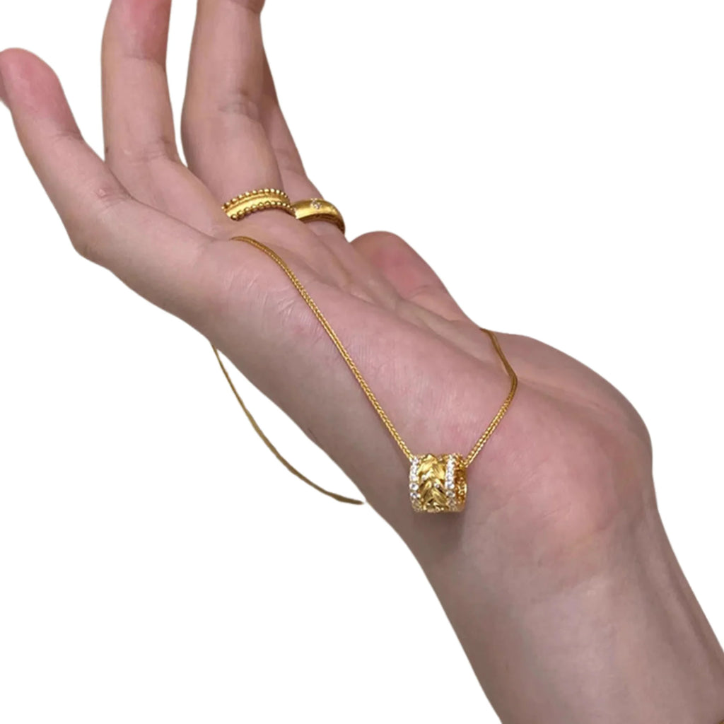 Detail des floralen Zylinderanhängers – filigran durchbrochen, goldfarben, strukturiert gearbeitet